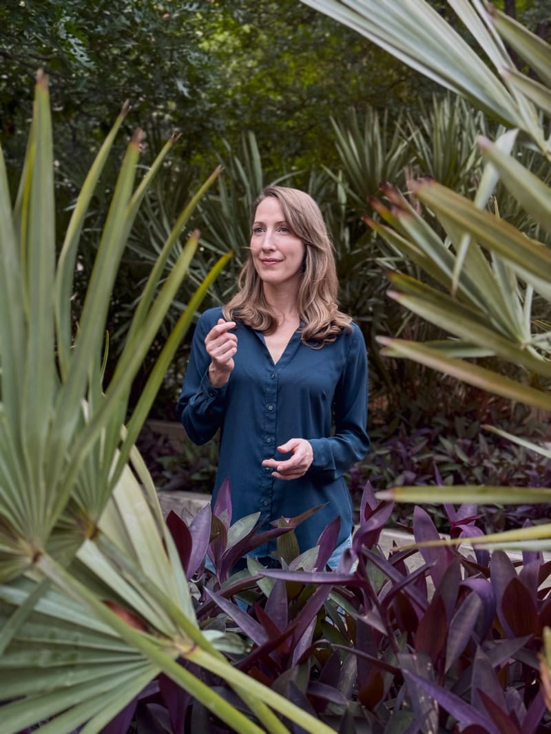 Erin Warner mid-conversation in a garden of palms and purple foliage
