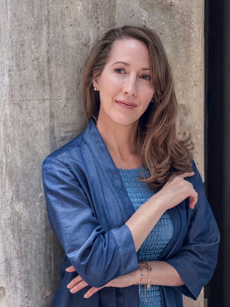 Erin Warner, executive coach and facilitator, leaning against a concrete wall